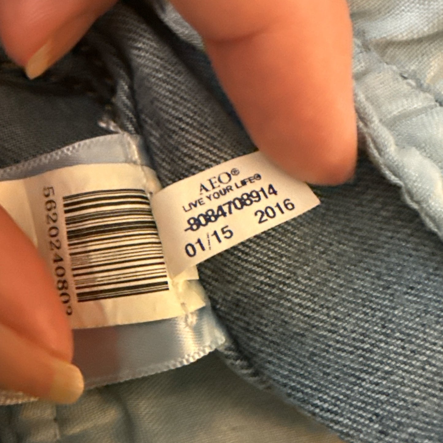 Close-up of a clothing label on denim fabric with visible text and numbers.