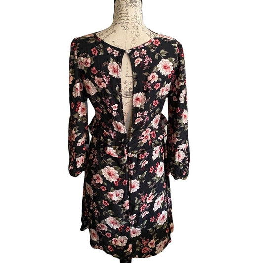 A black long-sleeve floral dress displayed on a vintage-style mannequin torso against a plain white background.