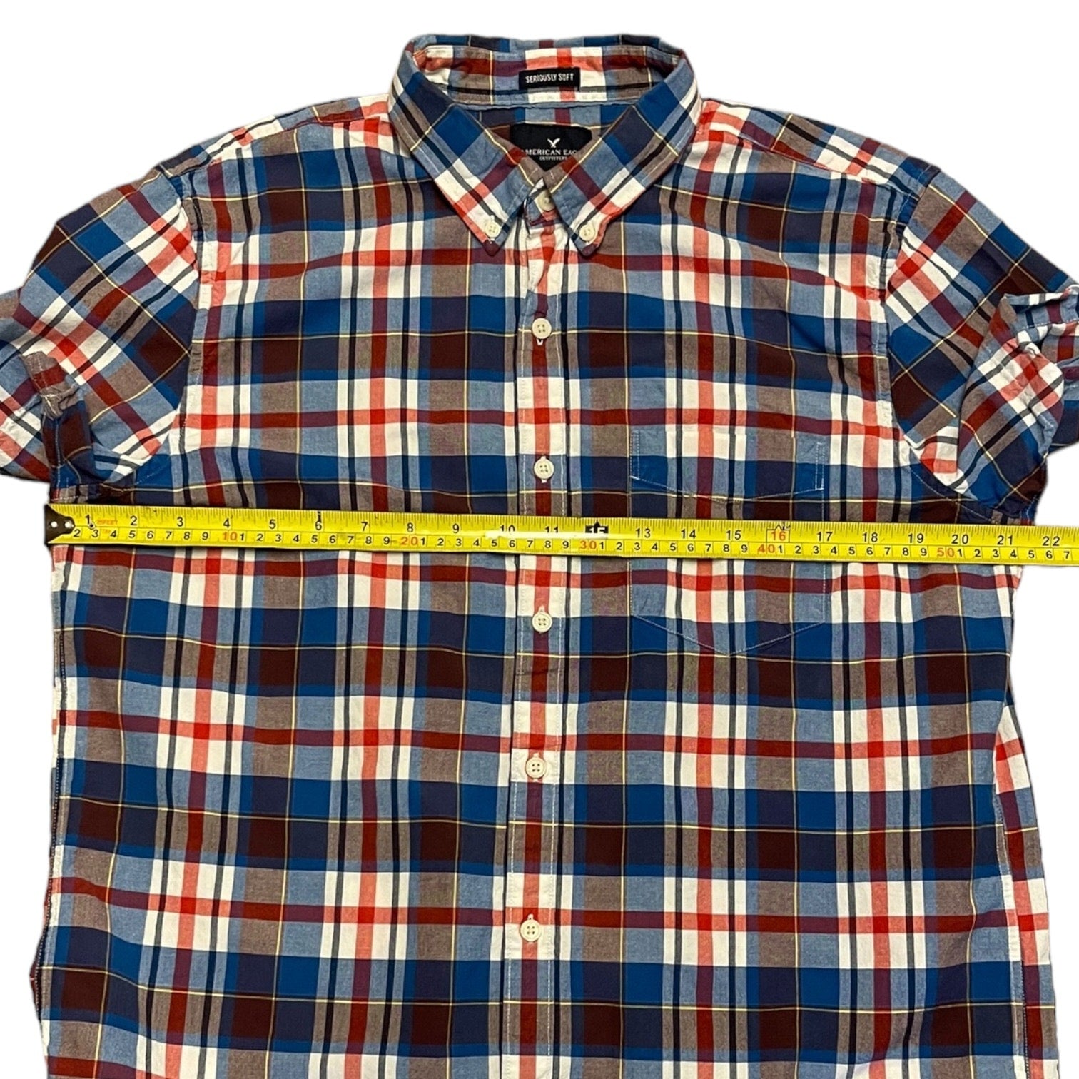 Plaid shirt with a measuring tape laying across it on a white background