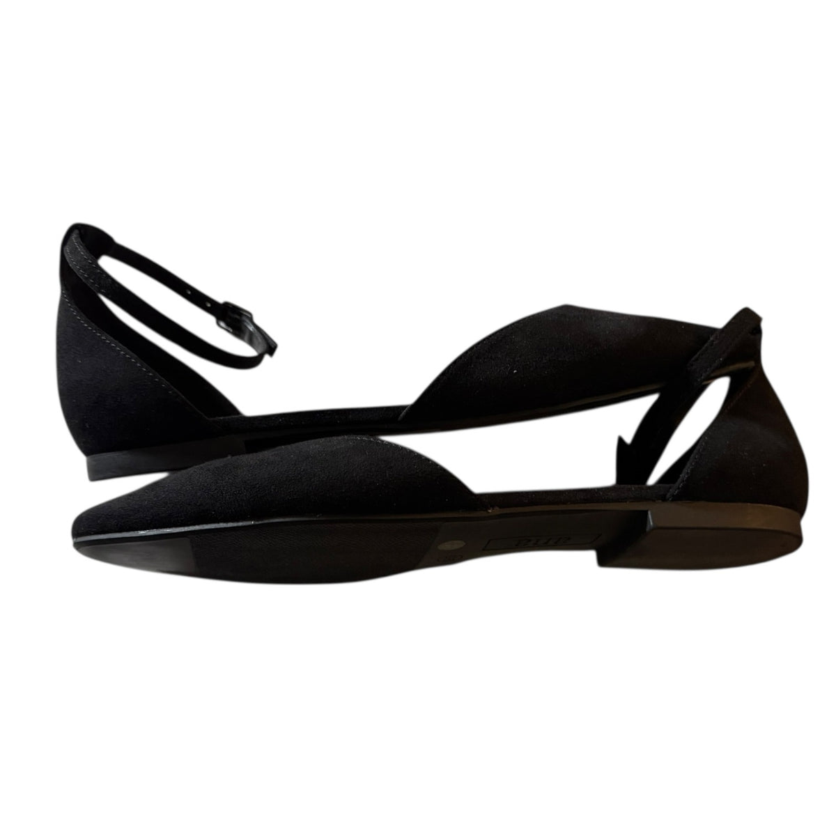 A pair of black flat sandals with a pointed toe, open side straps, and a thin ankle strap with a buckle, shown against a plain white background.