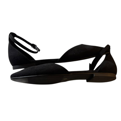 A pair of black flat sandals with a pointed toe, open side straps, and a thin ankle strap with a buckle, shown against a plain white background.