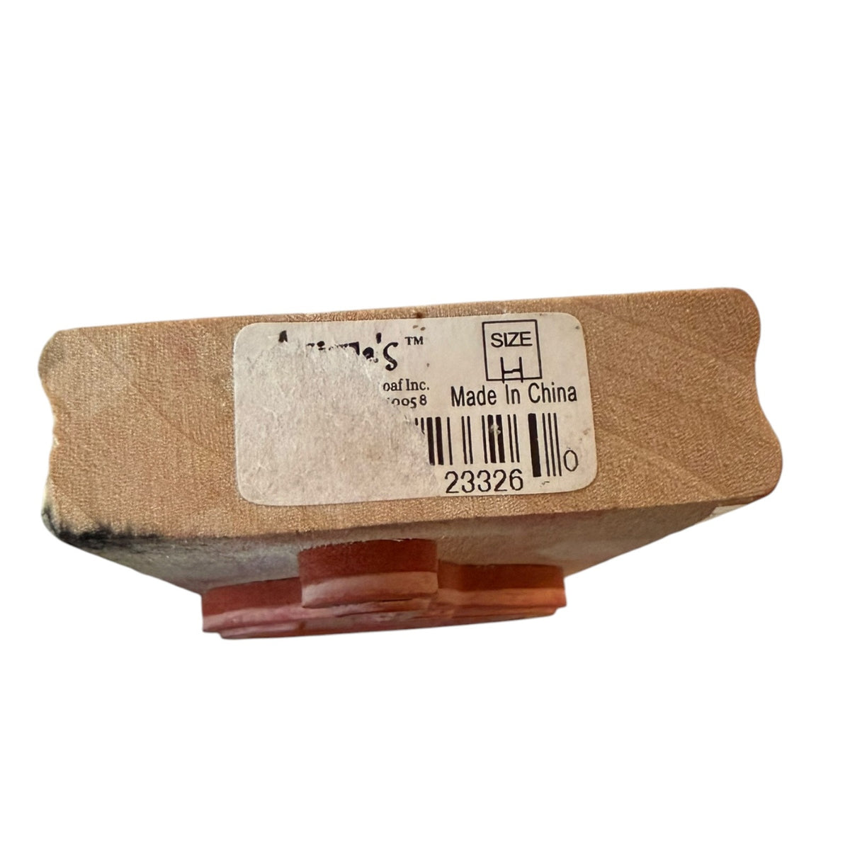 Side view of a rubber stamp on a white background with a torn label on a wood block. 