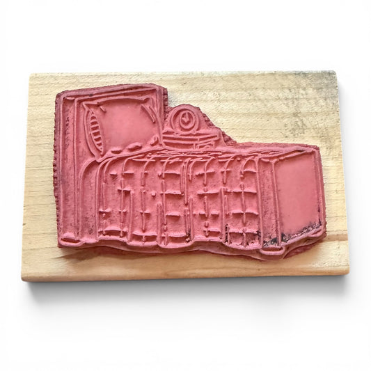 Pink rubber stamp on a wooden block with a white background