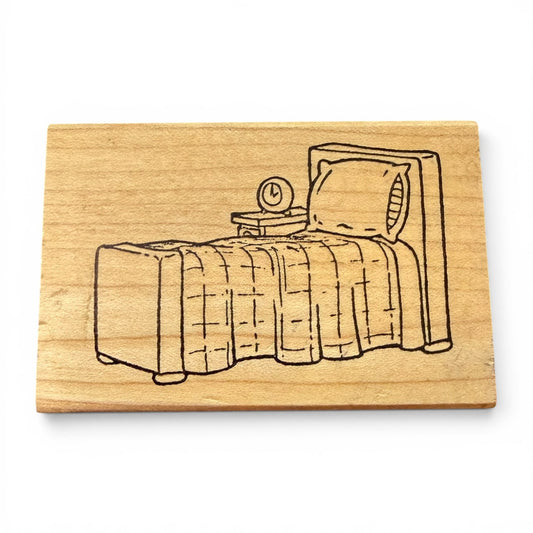 Wooden stamp with a bed illustration on a white background