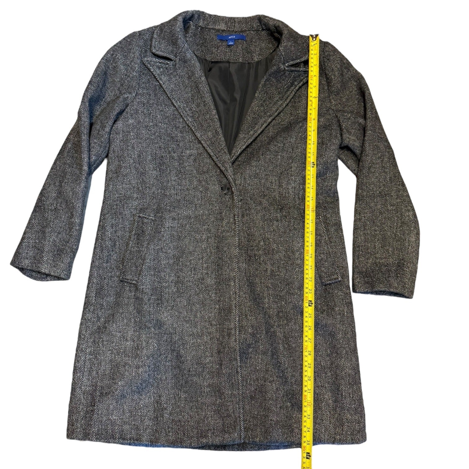Overcoat laying flat with a measuring tape showing length