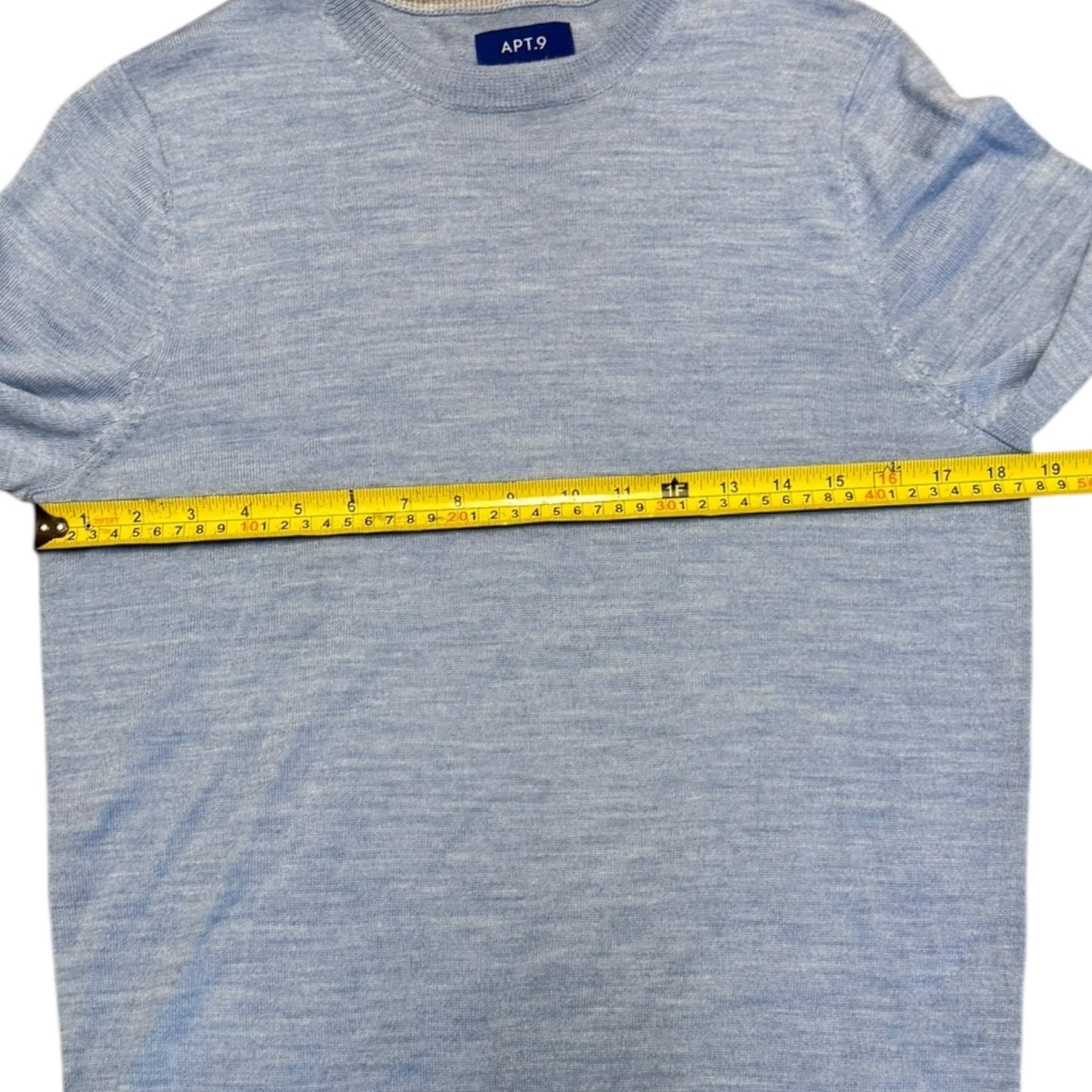 Blue sweater with a measuring tape across it, on a white background