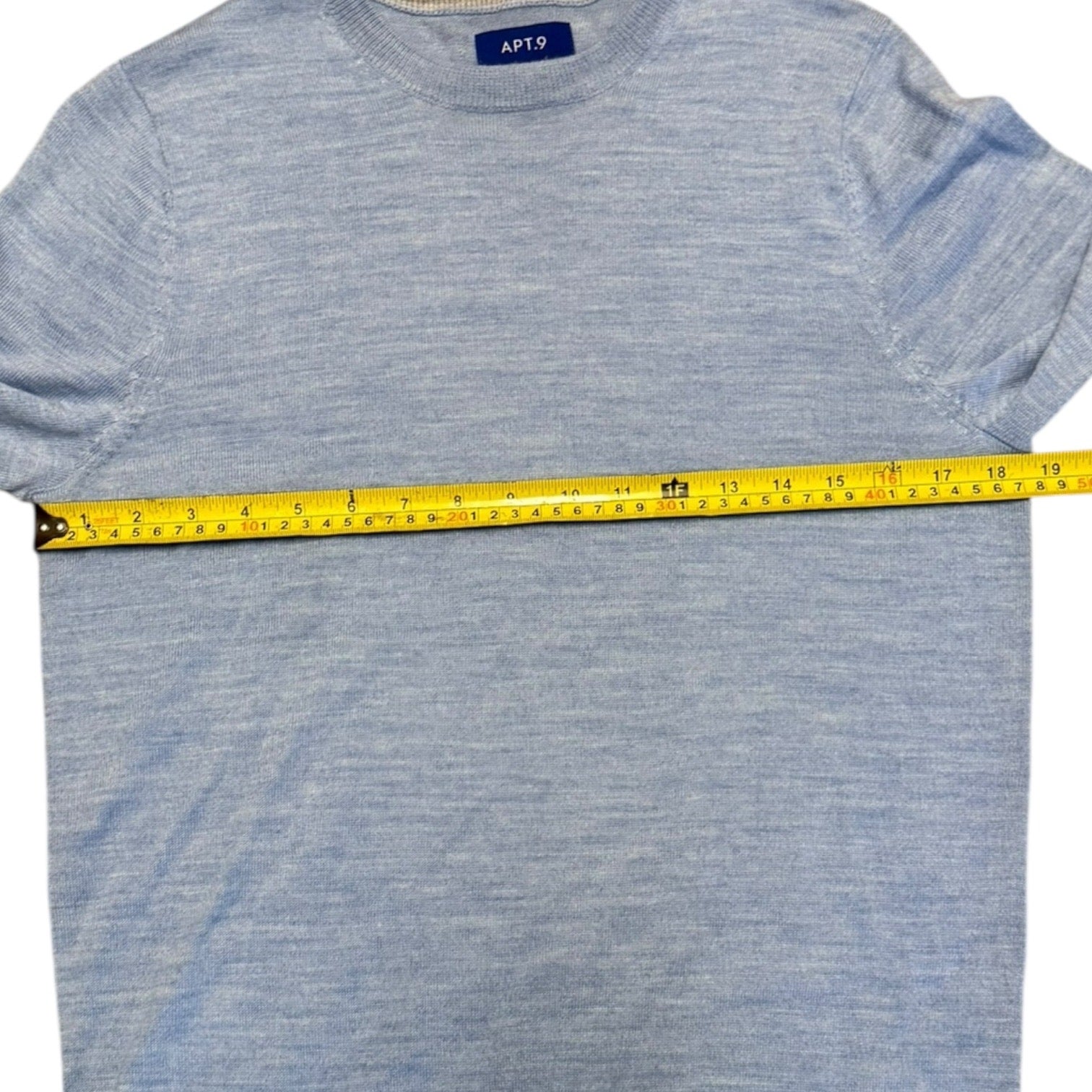 Blue sweater with a measuring tape across it, on a white background