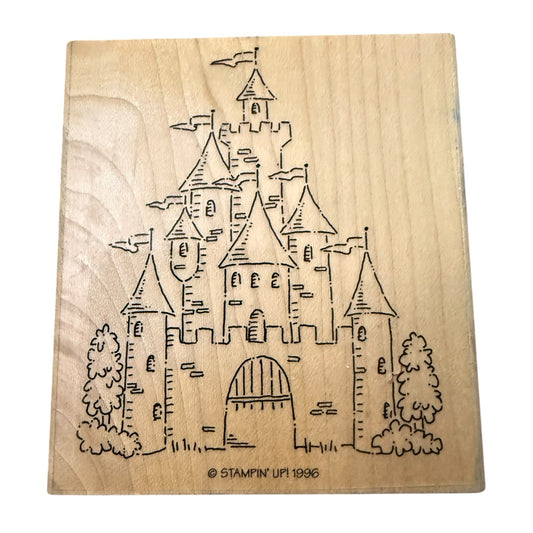 A square natural wood stamp block featuring a drawing of a castle with towers, flags, trees, and an arched gate. Small text at the bottom reads “© STAMPIN' UP! 1996.