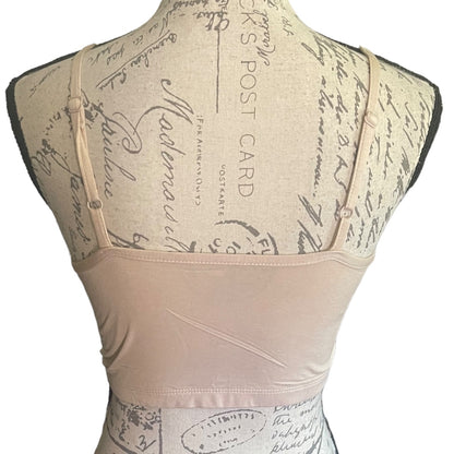 A beige bralette displayed on a vintage-style dress form mannequin, showing the back view with adjustable shoulder straps and a wide waistband.