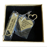Silver heart-shaped pendant with engraved text , displayed in a box.