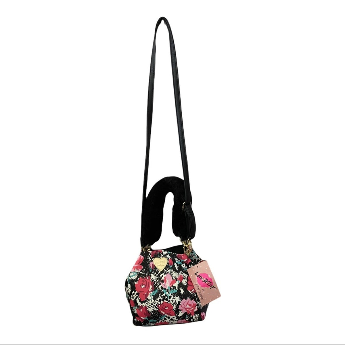 A small crossbody handbag with a black floral print, featuring a black faux-leather shoulder strap, a black curved handle, and a pink brand tag on a white background.