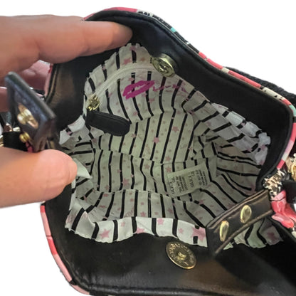 Close-up of the interior of a handbag being held open by a hand. The bag with a pink floral pattern on the edges and a striped lining with pink stars and a small zip pocket.