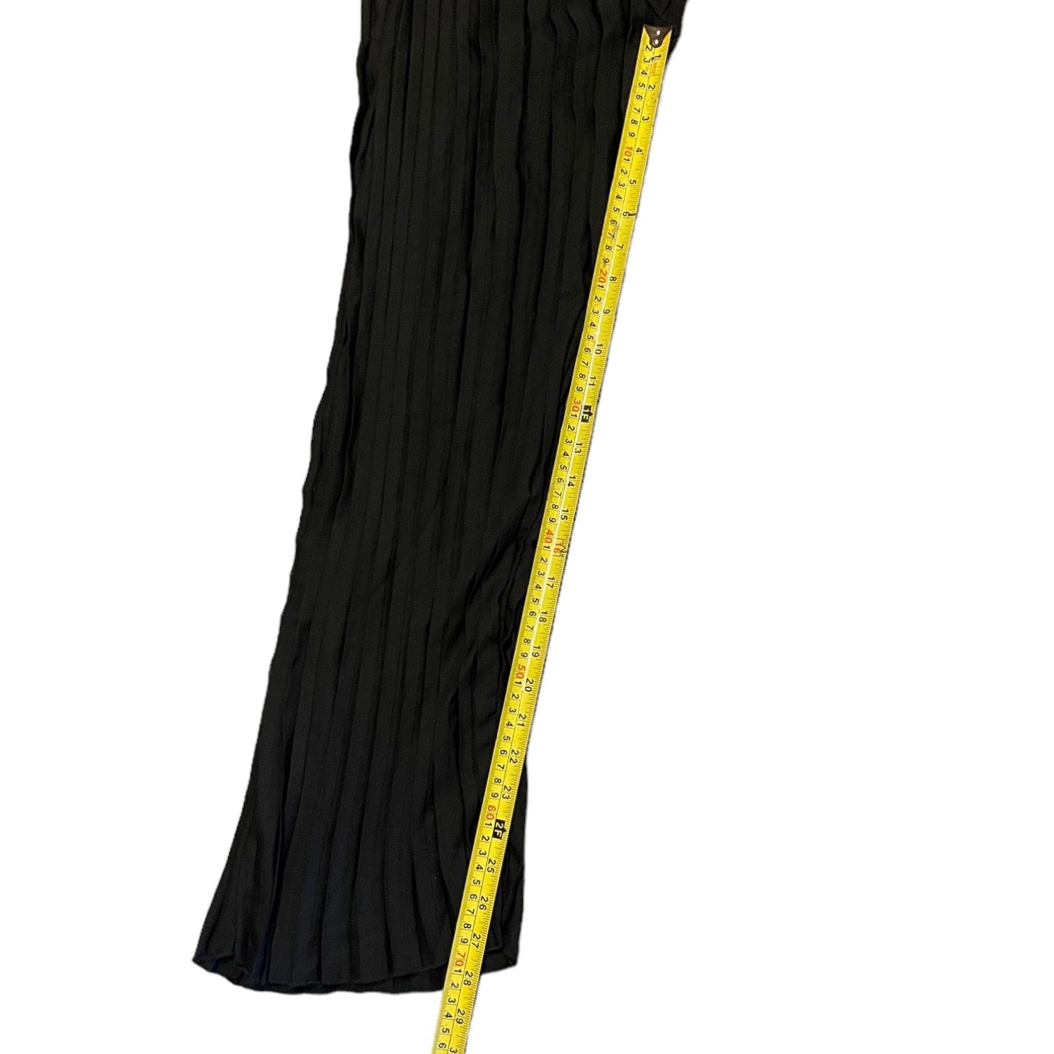 A black pleated black pant cover up against a white background with a yellow measuring tape running vertically to indicate size.