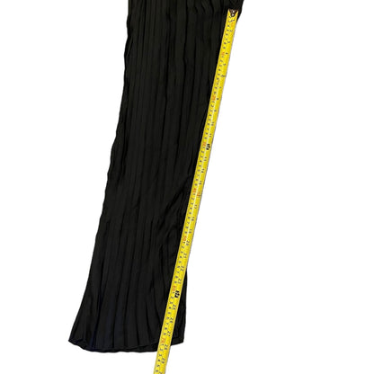 A black pleated black pant cover up against a white background with a yellow measuring tape running vertically to indicate size.