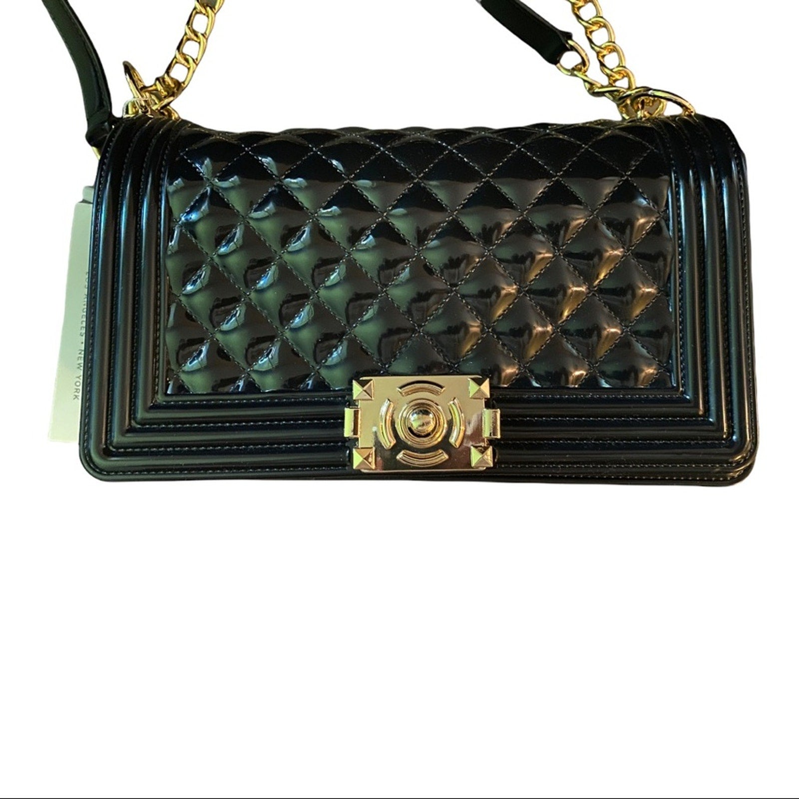 Close up of Black quilted handbag with gold accents on a white background