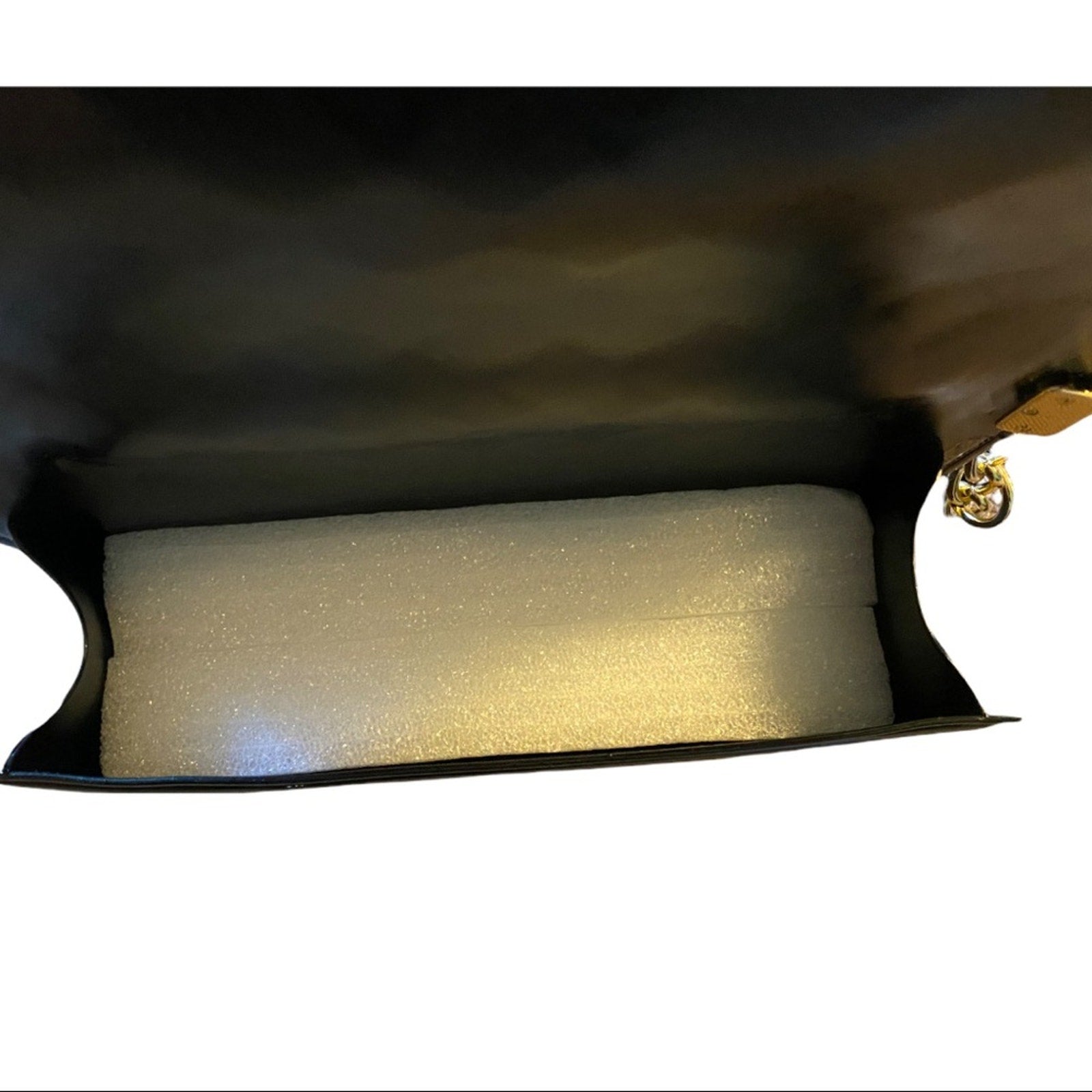 Foam block inside interior of black purse on a white background