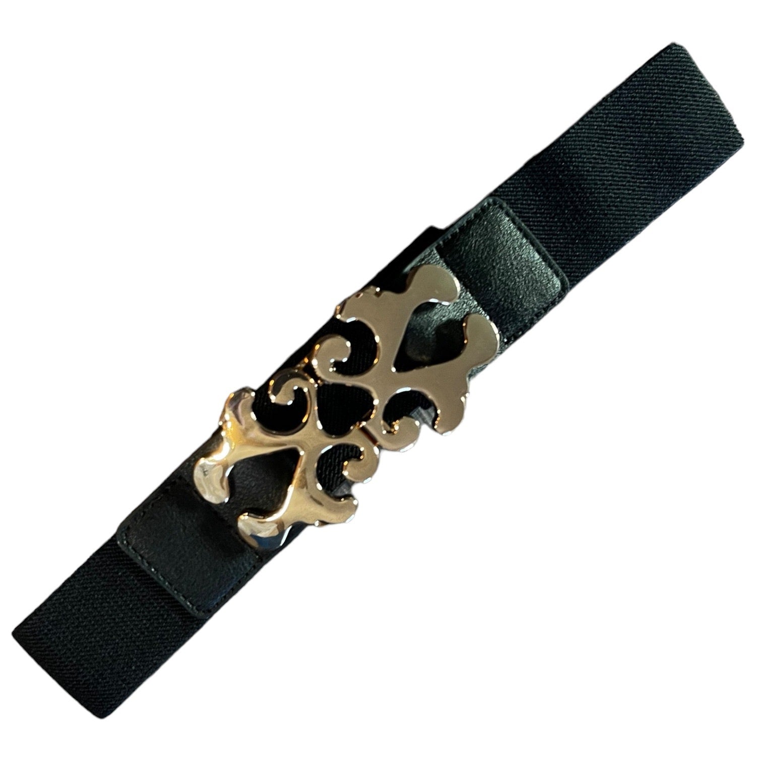 A black elastic belt with a decorative gold metal buckle featuring a stylized cutout design, shown on a plain white background.