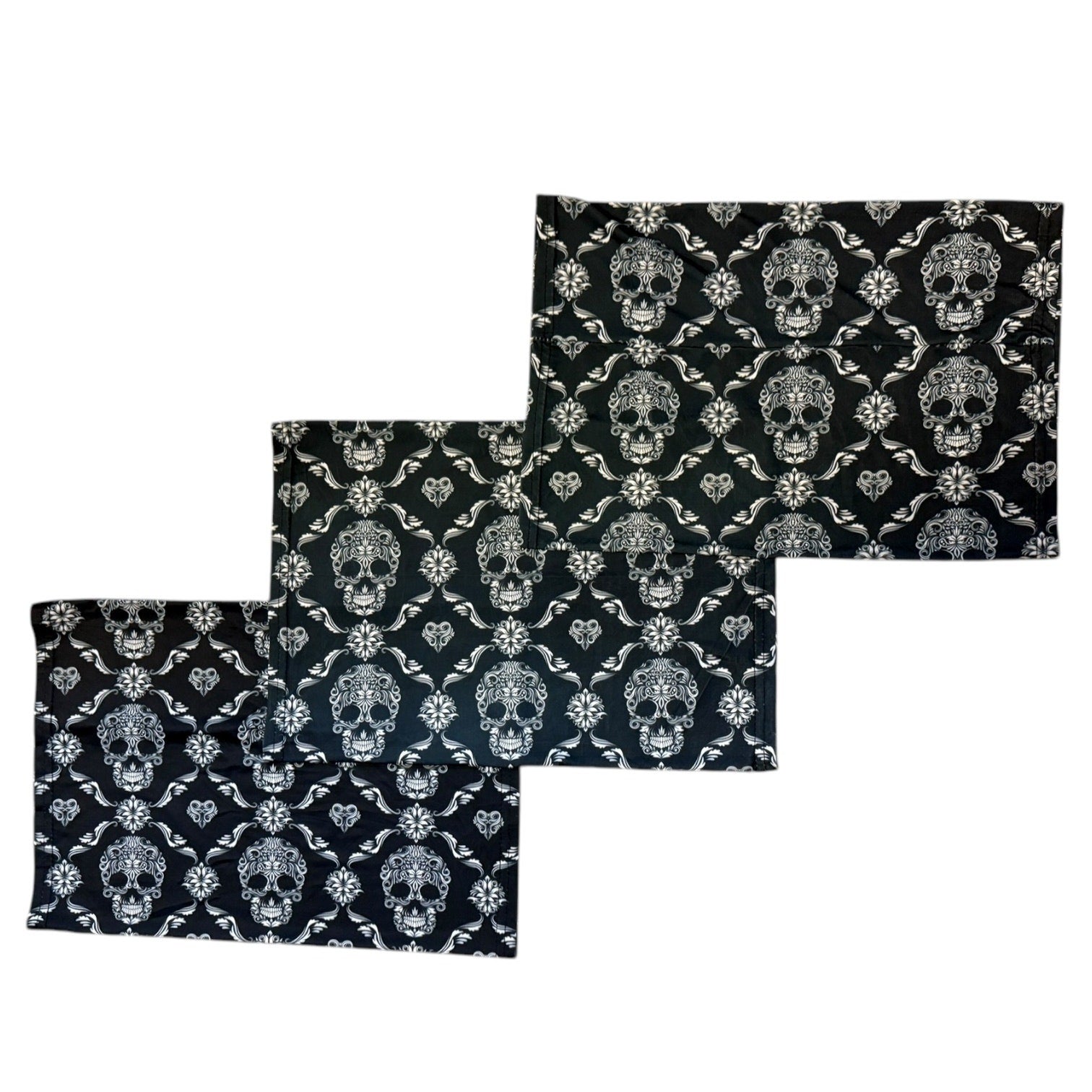 Set of three black and white skull patterned face masks on a white background