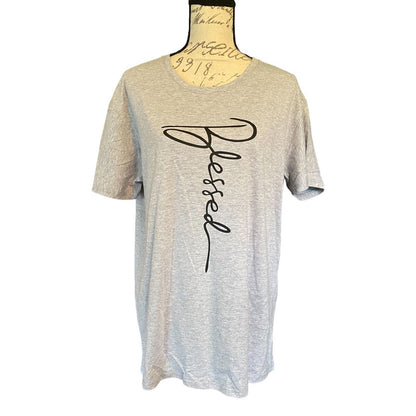 A light heather gray short-sleeve t-shirt . The shirt features a large black cursive script graphic spelling 'Blessed' vertically on the front.