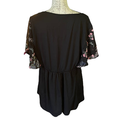 Back of black shirt with floral sleeves on a mannequin against a white background