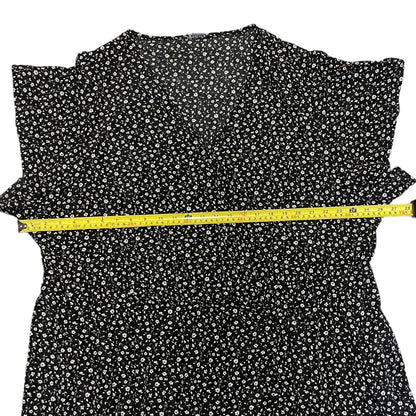 Black dress with white floral pattern and a measuring tape on a white background