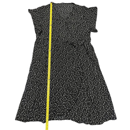 Black dress with white floral pattern and a yellow measuring tape on a white background
