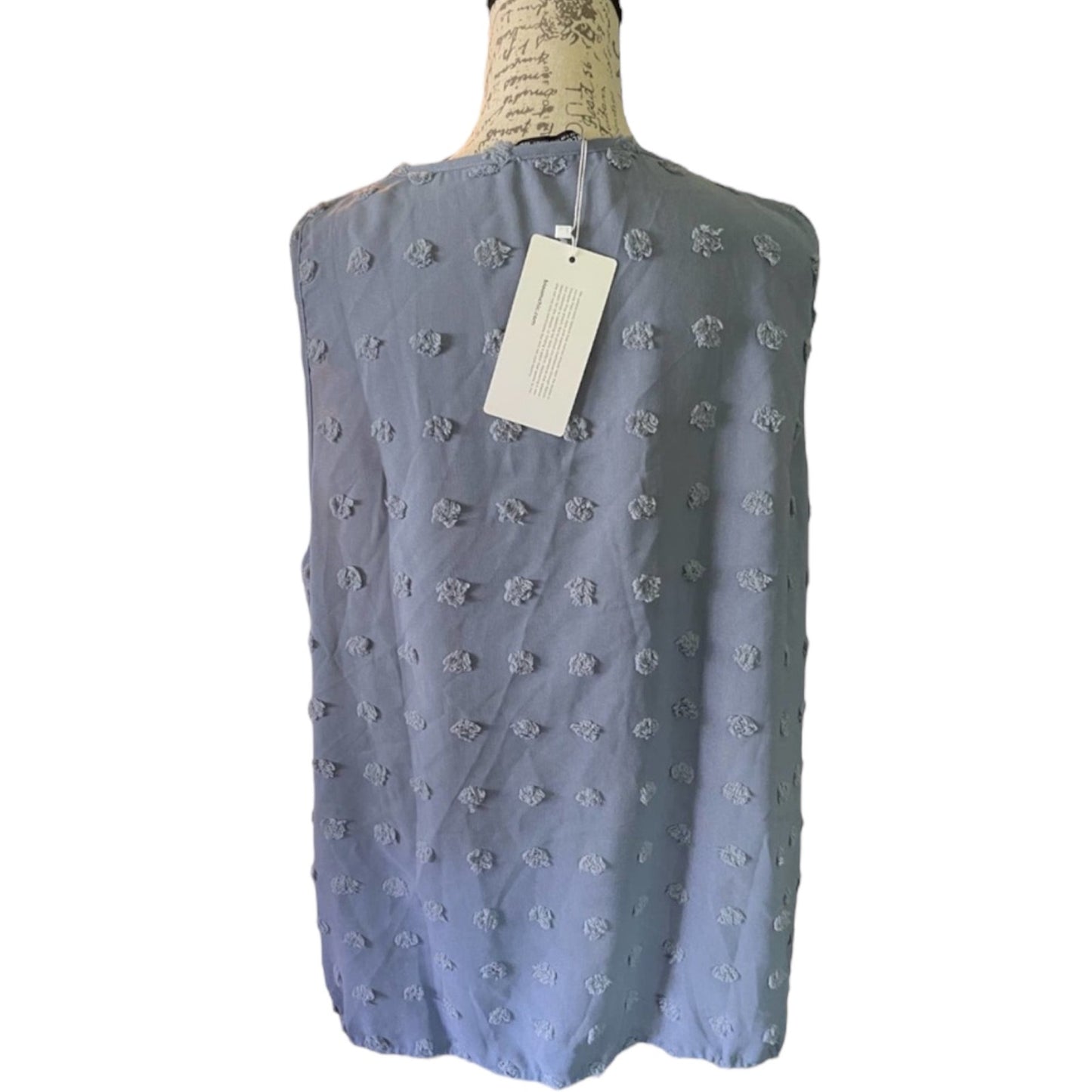 Light blue sleeveless top with polka dot pattern on a mannequin with a tag, white background