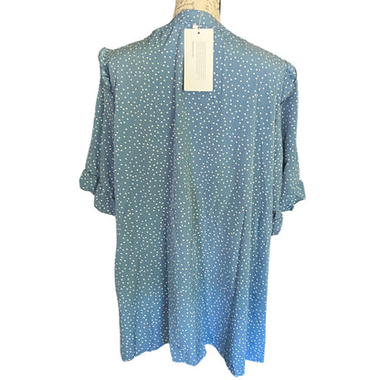 Back of Blue polka dot blouse on a mannequin with a tag against a white background