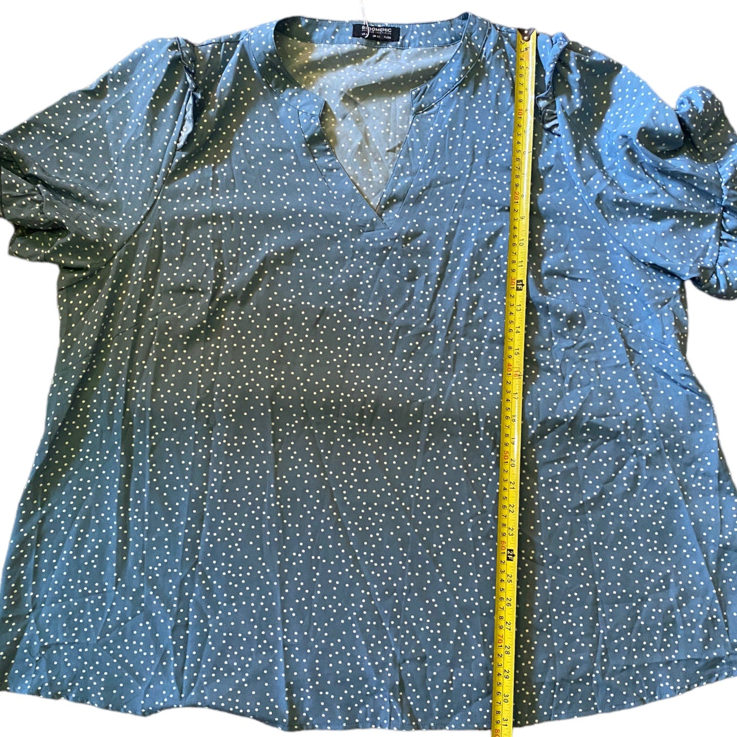 Blue polka dot blouse with a measuring tape on a white background
