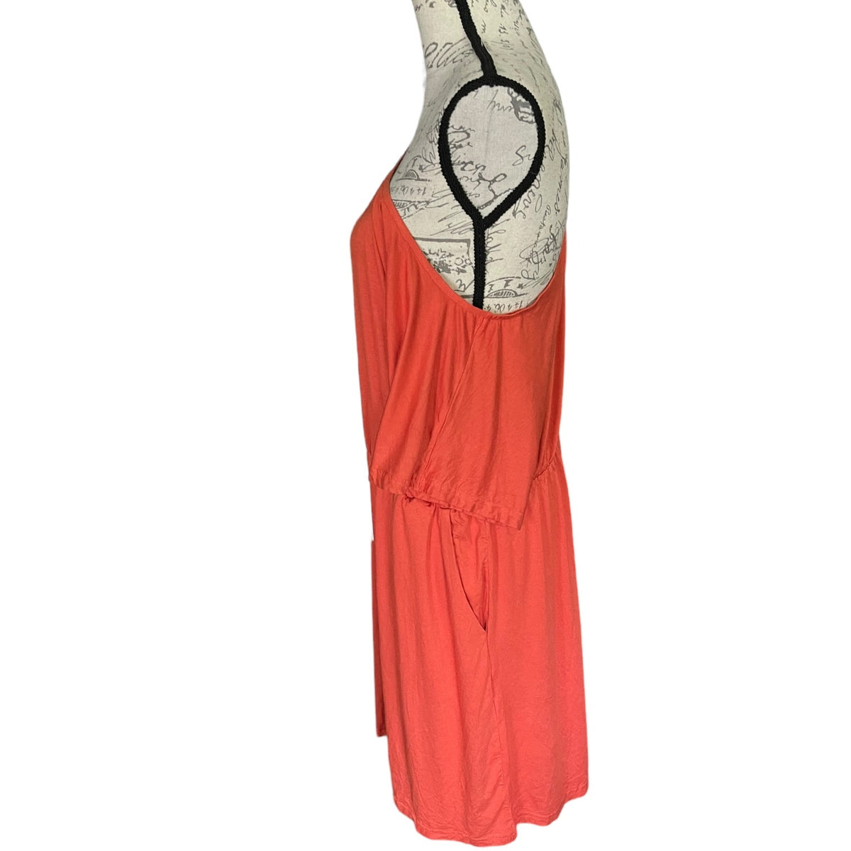 A side view of off shoulder coral orange romper displayed on a vintage-style dress form mannequin against a plain white background.
