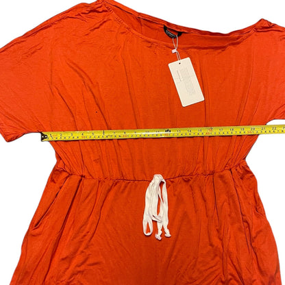 An orange short-sleeve romper laid flat on a white background, with a yellow measuring tape stretched horizontally across the chest and a white drawstring at the waist.