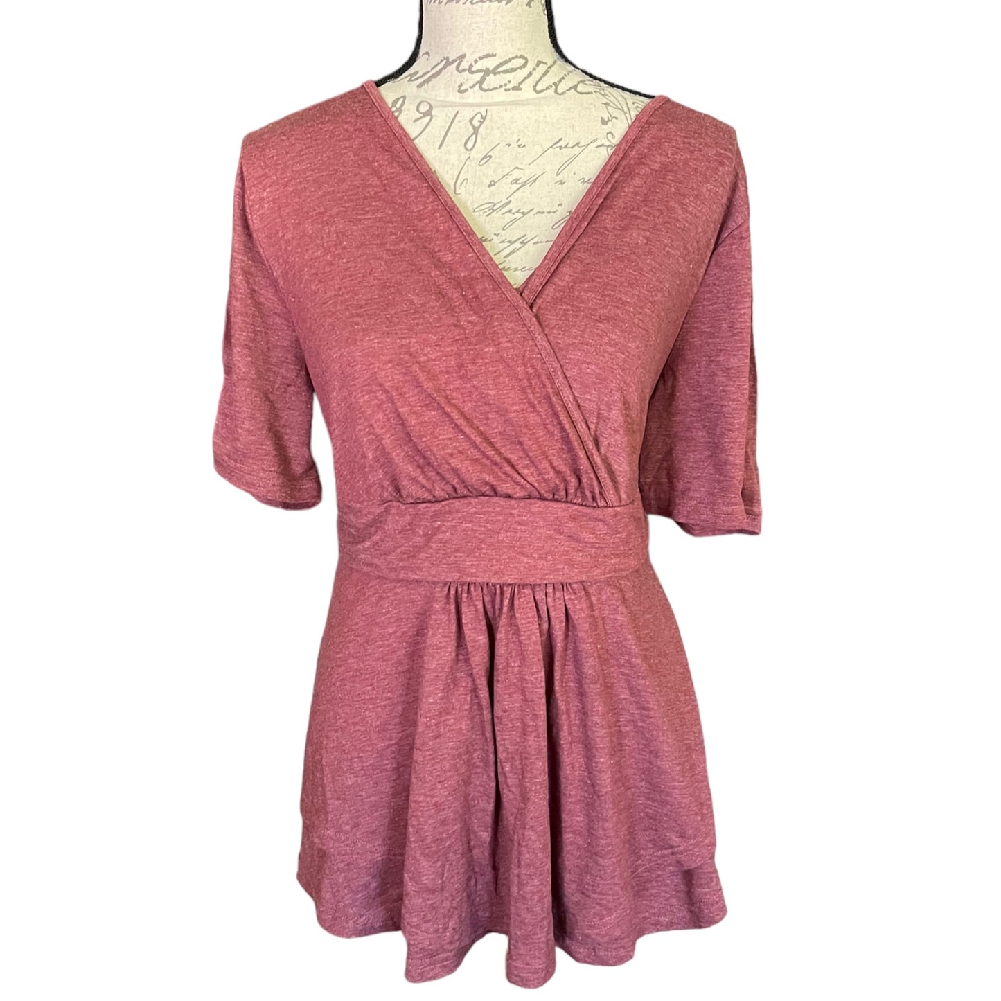 A heathered dusty rose pink short-sleeve wrap shirt displayed on a vintage-style mannequin torso against a plain white background.