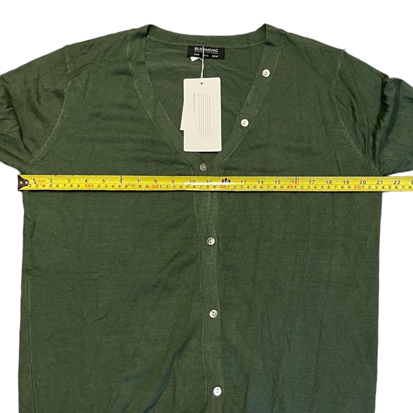 Green sweater with a measuring tape and tag on a white background