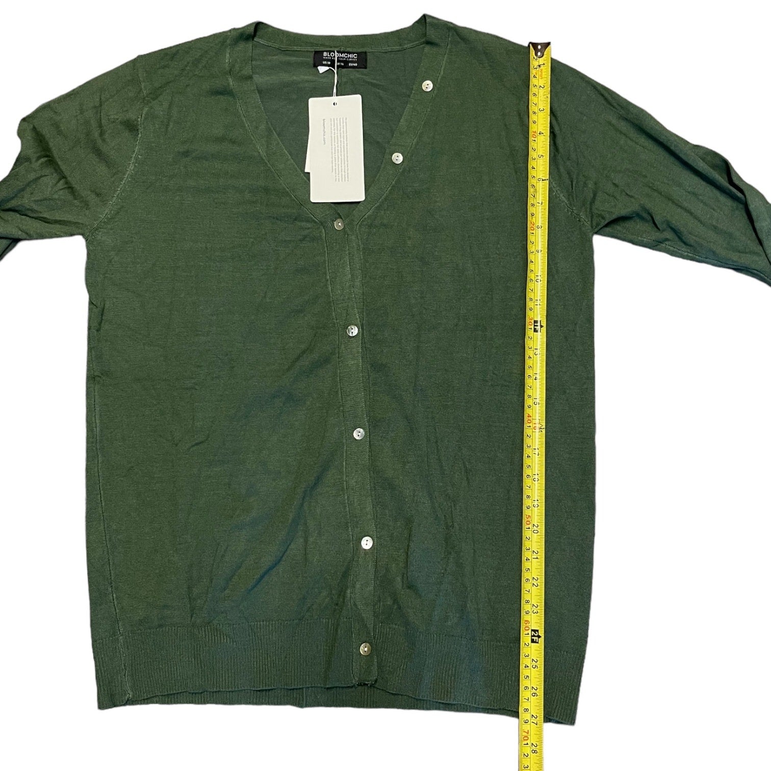 Green cardigan with a measuring tape on a white background