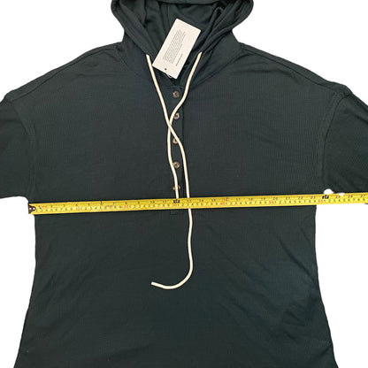 Dark green hoodie with a measuring tape draped over it on a white background