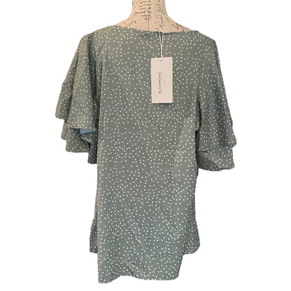 Back of Green polka dot dress on a mannequin with a visible brand tag against a white background