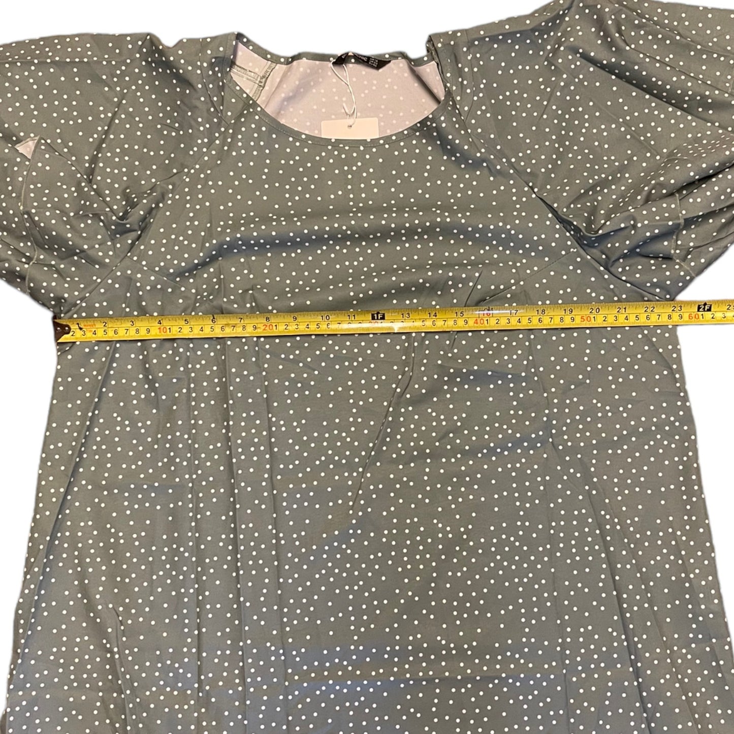 Green shirt with white polka dots and a measuring tape on it