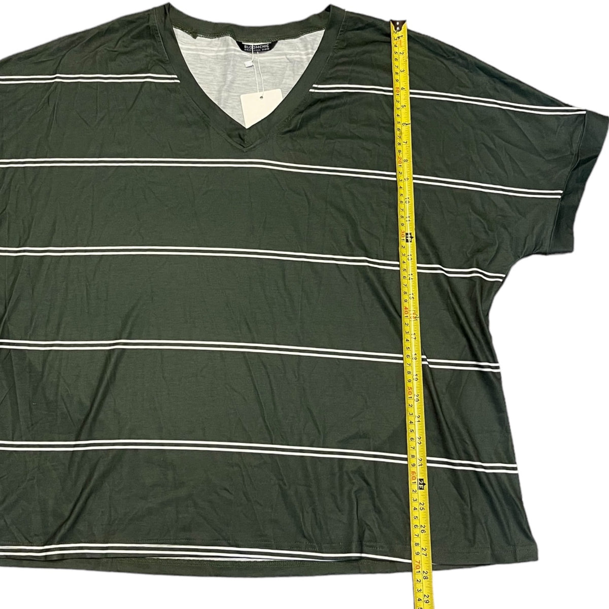 An green short-sleeve V-neck t-shirt with thin white horizontal stripes, shown flat on a white background with a yellow measuring tape running vertically to indicate size.