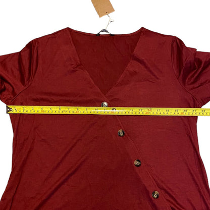 A maroon short-sleeve V-neck top with a button-front wrap style, shown with a yellow tape measure stretched horizontally across the chest to indicate size.