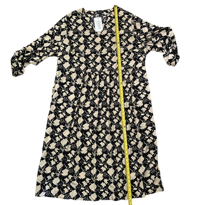 A black and beige floral print dress , shown flat on a white background with a yellow measuring tape running down the center to indicate size.