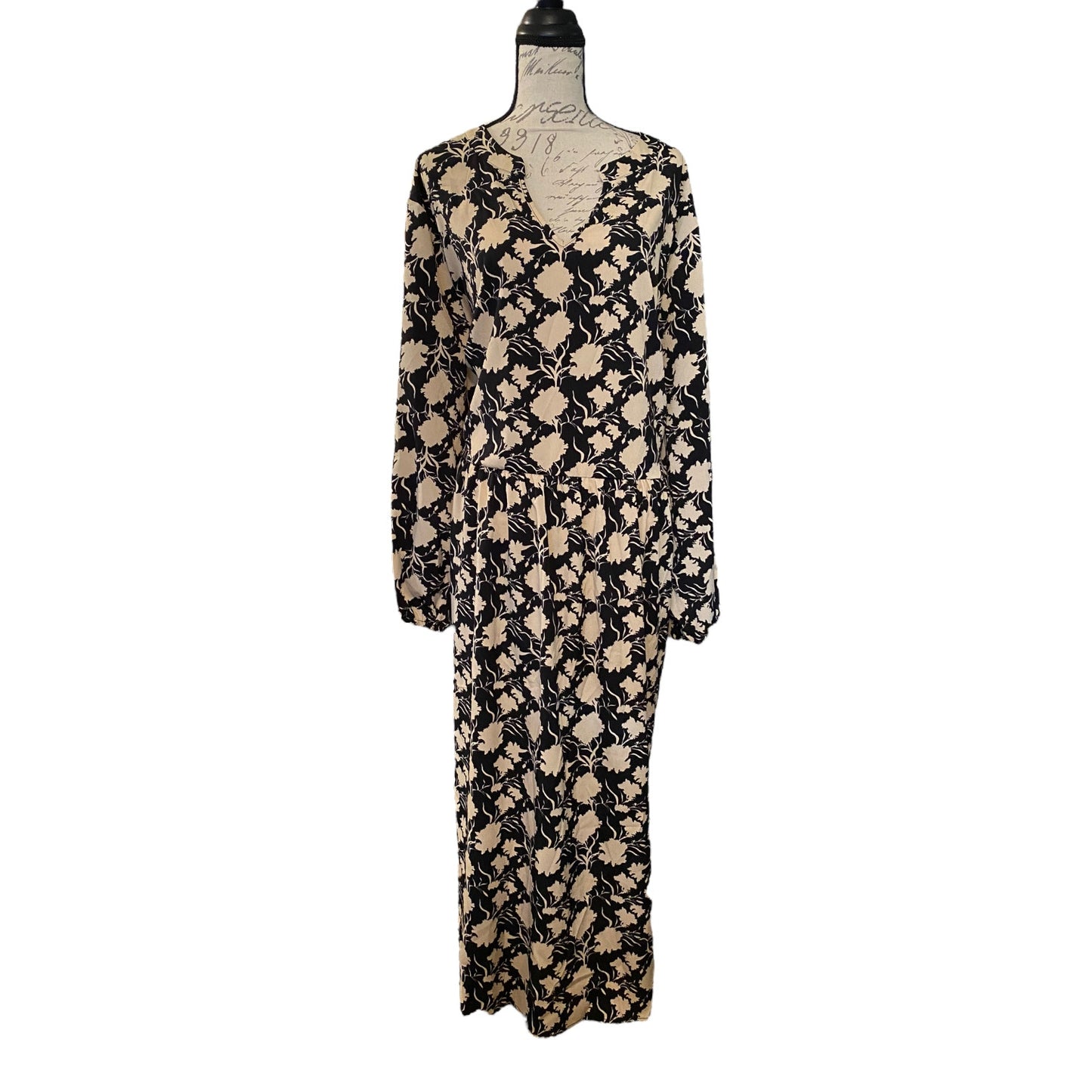 A long-sleeve dress with a black and beige abstract floral pattern, displayed on a dress form mannequin against a plain white background.