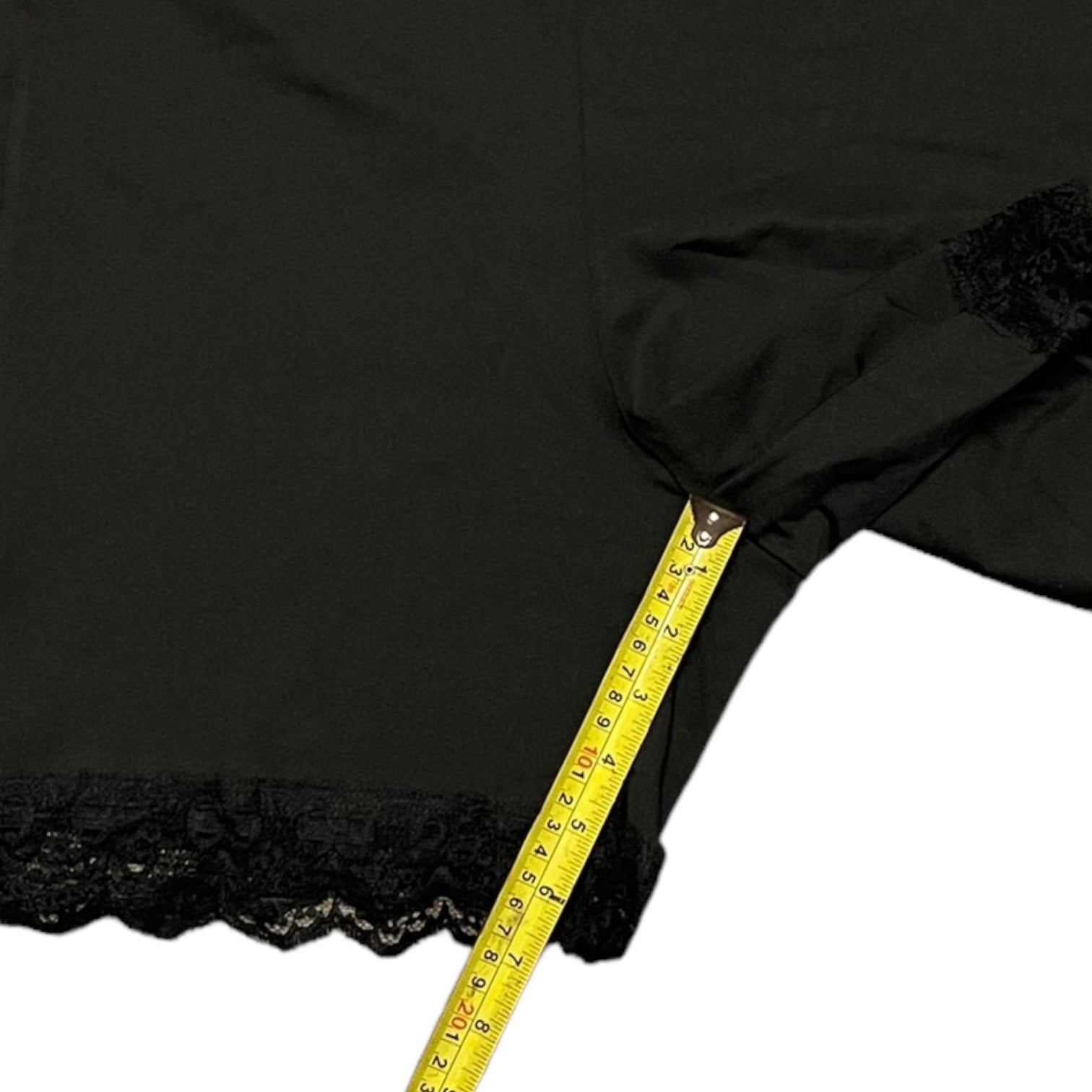 Black fabric with lace trim and a yellow measuring tape draped over it on a white background