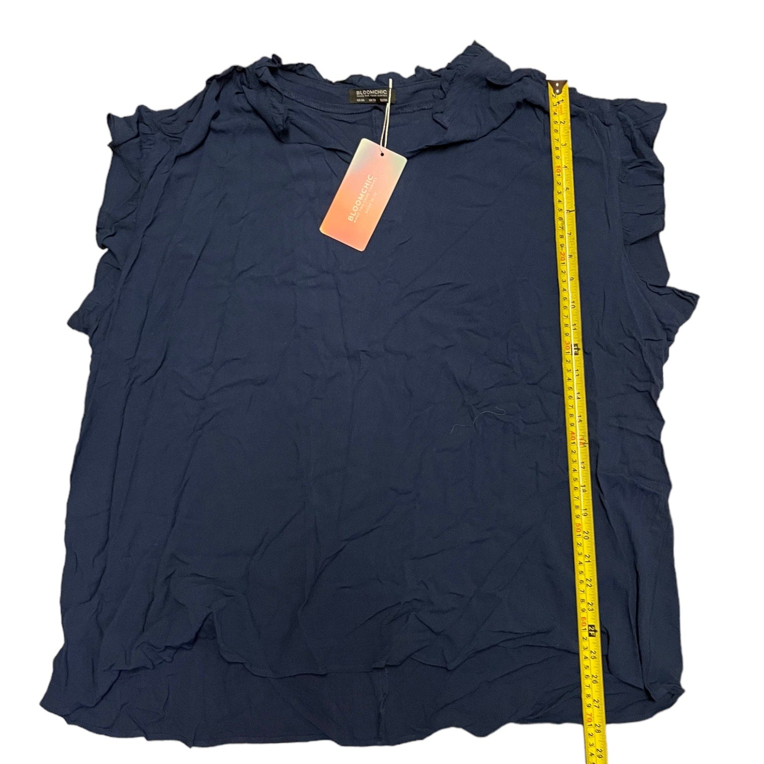 Navy blue sleeveless top with ruffled details and a measuring tape on a white background