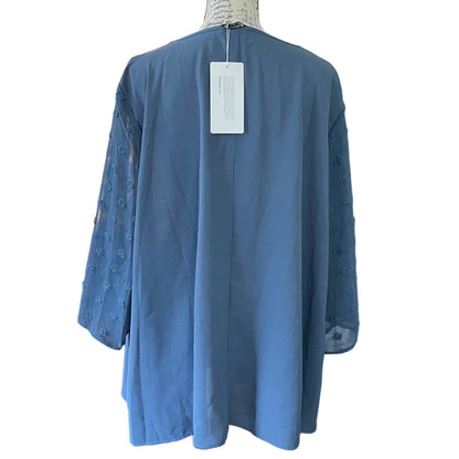 A blue long-sleeve blouse shown from the back on a dress form, featuring textured floral embroidery on the sleeves and a white hangtag attached at the neck.