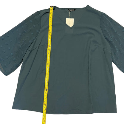  long-sleeve blouse with textured, raised dot patterns on the sleeves, shown flat with a yellow measuring tape vertically aligned on the left side for scale.