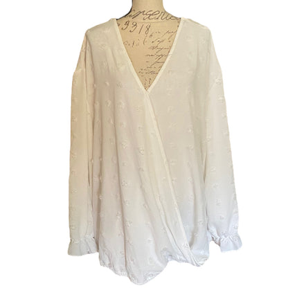 White polka dot long-sleeve top on a mannequin with a white background