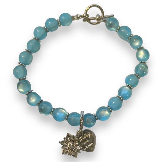 Blue beaded bracelet with a heart-shaped and snowflake charm on a white background