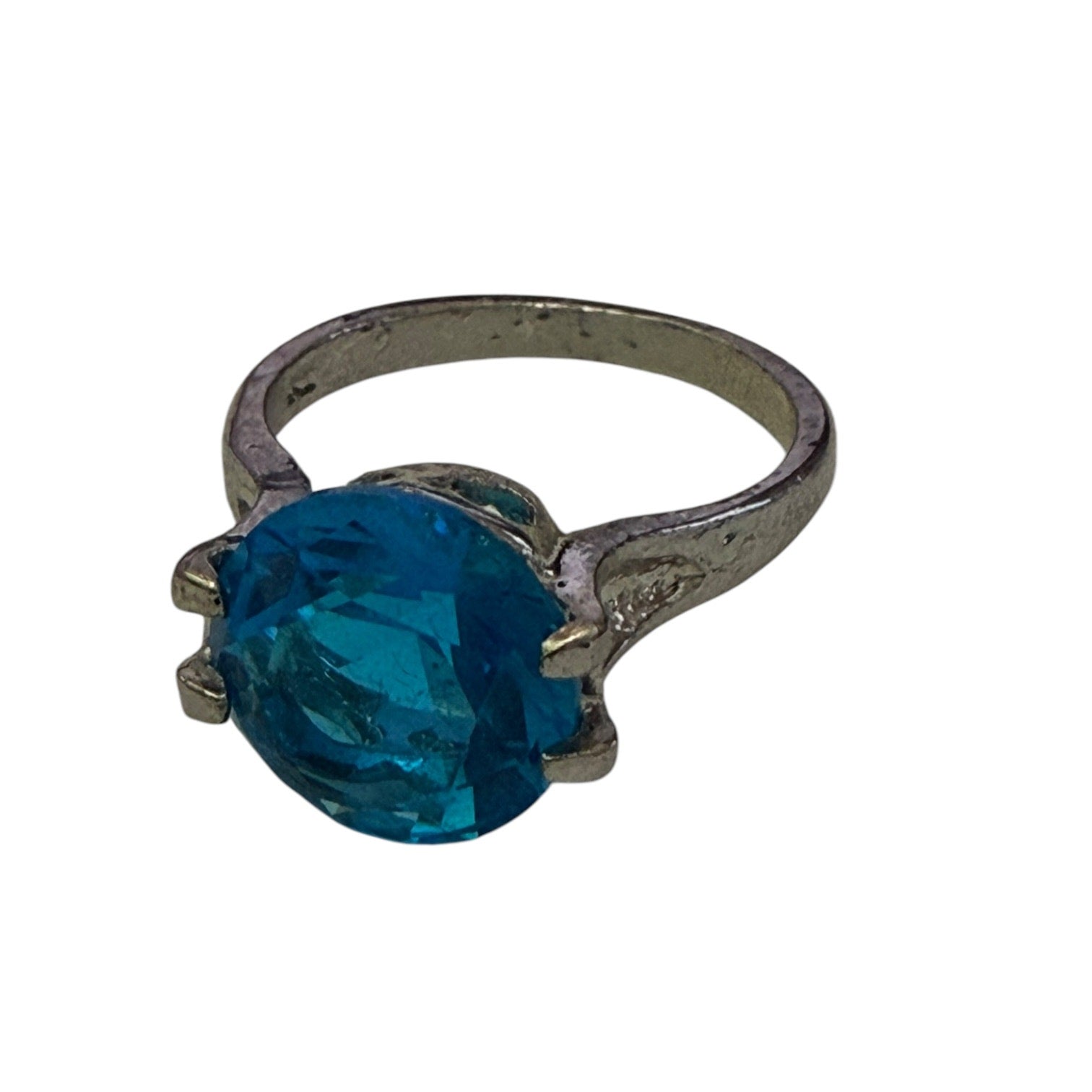 A silver-toned ring featuring a large, round-cut blue stone in a prong setting, shown against a plain white background.