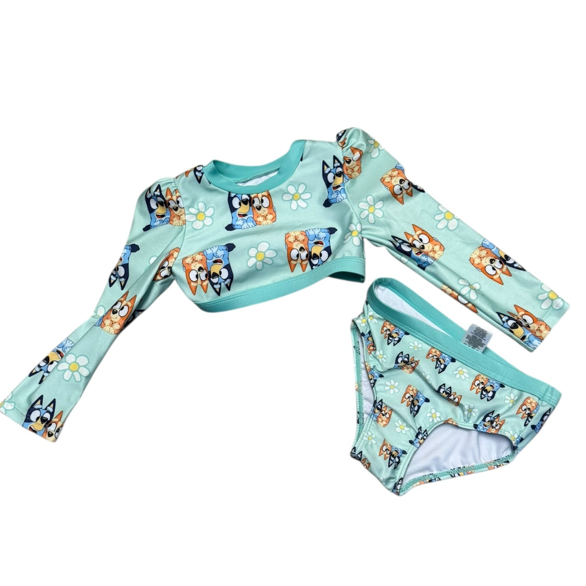 A two-piece children's swim set featuring a long-sleeve crop top and matching bikini bottoms in light mint green with a cartoon dog and daisy print, displayed on a solid white background.