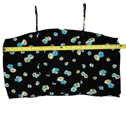 A black spaghetti-strap crop top with a colorful floral pattern, shown with a yellow tape measure across the chest to indicate size.